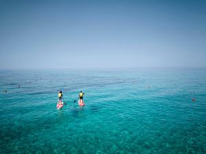 two people are on paddle boards in the ocean at Calaserena Resort in Geremèas