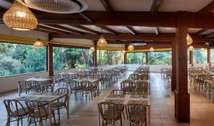 a dining room with tables and chairs and windows at Calaserena Resort in Geremèas