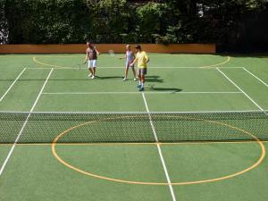 a group of people standing on a tennis court at Calaserena Resort in Geremèas