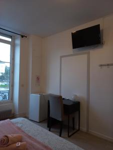 sypialnia z biurkiem i telewizorem na ścianie w obiekcie Hôtel Labat w mieście Orthez