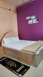 Ce lit se trouve dans un dortoir doté d'un mur violet. dans l'établissement KonkanParadise,Hotel Malvan Beach, à Malvan