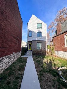 a white house with a yellow door and a brick building at Modern House with Terrace Near Forest Park in Saint Louis