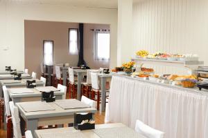 uma sala de jantar com mesas brancas e cadeiras brancas em Pousada Paraíso em Cambará