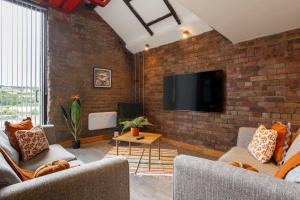 a living room with two couches and a brick wall at Broadgate Penthouse Apartment in Bradford