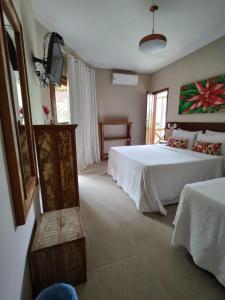 a bedroom with two beds and a television in it at Pousada Caiçara in Abraão