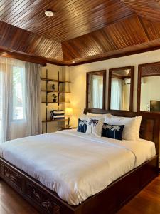a bedroom with a large bed with a wooden ceiling at Galayanee’s Resort Apartment in Seminyak