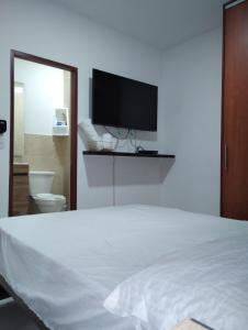 1 dormitorio con 1 cama blanca y TV de pantalla plana en Mirador Piso 17 - Acogedor y Exclusivo apartamento en piso 17 con vista al mar, en Cartagena de Indias