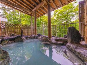a hot tub in a backyard with a wooden pergola at Hotel Oakhill in Zaō Onsen