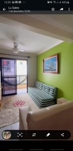 ein Wohnzimmer mit einem Sofa und einer grünen Wand in der Unterkunft Guarapari Enseada Azul in Guarapari