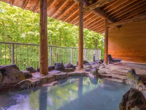 a swimming pool in a backyard with a wooden porch at Hotel Oakhill in Zaō Onsen