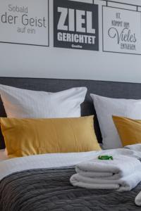 uma cama com lençóis brancos e almofadas amarelas em Goethe Palais Suite Anna Amalia l 1-8P l Lift l Parkplatz em Aue