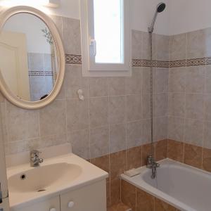 ein Badezimmer mit einem Waschbecken, einer Badewanne und einem Spiegel in der Unterkunft Superbe Maison 3 chambres, wifi, climatisation, Narbonne Plage in Narbonne-Plage