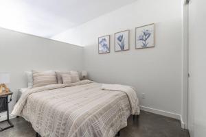 1 dormitorio blanco con 1 cama y 3 cuadros en la pared en Seattle Lux 1 bd Apartment- Rooftop, WiFi, Pet Friendly en Seattle