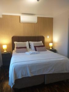 a bedroom with a large white bed with two lamps at Flat na Rua XV 2107 in Curitiba