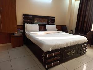 Haridwar Jbk by prithvi Yatra hotel and kedarnath في حاريدوار: غرفة نوم بسرير كبير مع اللوح الخشبي