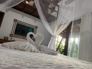 two swans are sitting on top of a bed at Manacá Flat in Itacaré