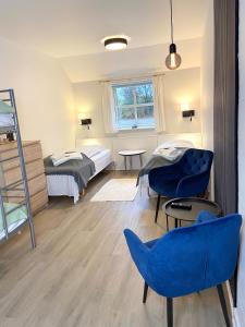 a room with two beds and blue chairs at Lille Grynborg in Blommenslyst