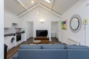 a living room with blue couches and a kitchen at Stylish Self-Contained Annex near City Centre in Southampton