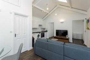 a living room with a blue couch and a kitchen at Stylish Self-Contained Annex near City Centre in Southampton