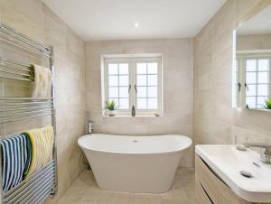 a bathroom with a white tub and a sink at The Hive - Pet Friendly House - Emsworth in Emsworth +17 photos