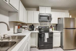 a kitchen with white cabinets and a stainless steel refrigerator at Centrally Located Apt about 2 Mi to University of Iowa in Iowa City