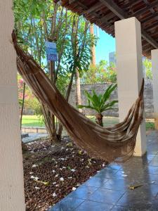 een hangmat op een patio met palmbomen bij Casa de Veraneio com Piscina Perto da Praia in Lauro de Freitas