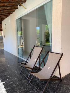 dwa krzesła siedzące na patio ze stołem w obiekcie Casa de Veraneio com Piscina Perto da Praia w mieście Lauro de Freitas