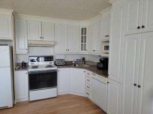 - une cuisine blanche avec des armoires blanches et des appareils noirs dans l'établissement Maison Miramar à 5 min de la Baie, à Sainte-Luce-sur-Mer