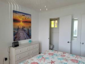 1 dormitorio con 1 cama y una pintura en la pared en Maison Miramar à 5 min de la Baie, en Sainte-Luce-sur-Mer