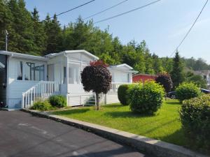 une maison blanche avec un arbre dans la cour dans l'établissement Maison Miramar à 5 min de la Baie, à Sainte-Luce-sur-Mer