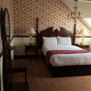 una camera d'albergo con un grande letto e un lampadario a braccio di Tides Apartments Liscannor a Liscannor