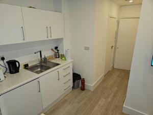 una cucina con armadi bianchi e lavandino di Luxury 1-Bed Apartment in London a Londra