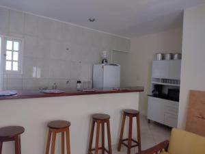 a kitchen with stools and a counter with a refrigerator at Apartamento 2 quartos em Conservatória - até 7 pessoas! in Conservatória