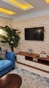 uma sala de estar com um sofá azul e uma televisão em Njoro Caves Holiday em Gichage