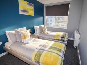 two beds in a room with blue walls and a window at Lytham Place in Preston