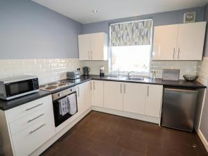 a kitchen with white cabinets and a microwave at Lytham Place in Preston