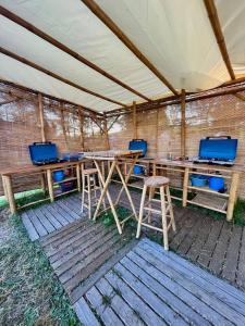 une tente avec des tables en bois et des tabourets en dessous dans l'établissement Lodg'ing Nature Camp Châteaux de la Loire, à Cellettes