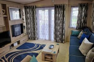 uma sala de estar com um sofá azul e uma televisão em Contemporary home at Tarka Holiday Park Barnstaple em Barnstaple