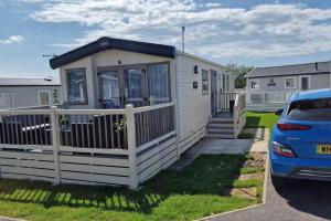 a small white house with a fence and a car at Contemporary home at Tarka Holiday Park Barnstaple in Barnstaple +10 photos