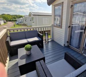 a patio with a couch and a table on a deck at Contemporary home at Tarka Holiday Park Barnstaple in Barnstaple