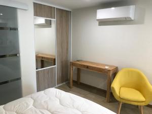 sypialnia z biurkiem i żółtym krzesłem w obiekcie Studio neuf de 24m² w mieście Brive-la-Gaillarde