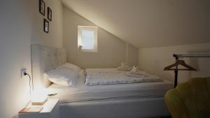 a white bedroom with a bed and a lamp at Hideaway Rooms & Apartments Sarajevo in Sarajevo