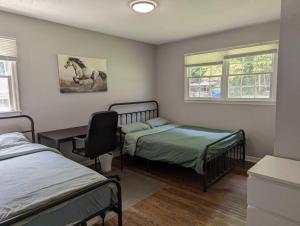 a bedroom with two beds and a chair and two windows at Cozy 3BR house near downtown Spartanburg. in Spartanburg