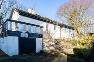 uma casa branca com uma porta de garagem preta e escadas em PleasantHillScotland-Stunning 7BR GardenVilla Superior Area (Sleeps24) em Milngavie