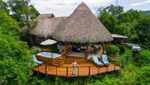 een terras met stoelen en een huis met rieten dak bij Isla Chiquita Glamping Hotel in Puntarenas