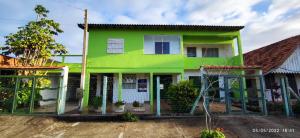 a green house with a fence in front of it at Apartamento família perto do mar in Tramandaí