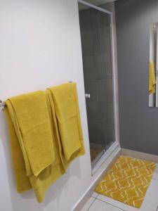 La salle de bains est pourvue d'une douche et de 2 serviettes jaunes. dans l'établissement 2@City Junction, à Windhoek