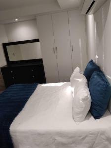 2@City Junction في ويندهوك: غرفة نوم مع سرير مع وسادتين زرقاوين