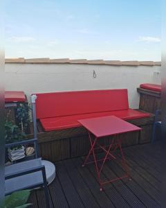 un banc rouge et une table sur un balcon dans l'établissement Chambres d'Hotes NATURISTE, Village Naturiste Cap d'Agde, Draps, Serviette, Café, Menage inclus en fin de sejour, au Cap d'Agde