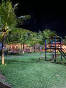 a park with a playground with palm trees at night at Apto Praia da Taíba Vista Mar in Taíba